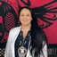 Smiling woman with long black hair and beaded jewelry.