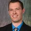 Smiling man in suit and blue shirt.