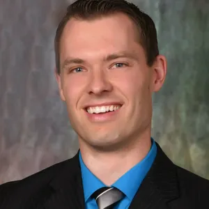 Smiling man in suit and blue shirt.