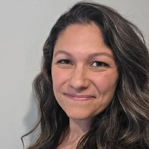 Smiling woman with long wavy hair.