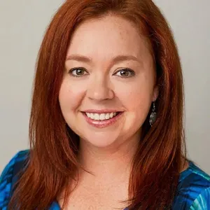 Smiling woman with red hair and earrings.