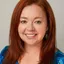 Smiling woman with red hair and earrings.